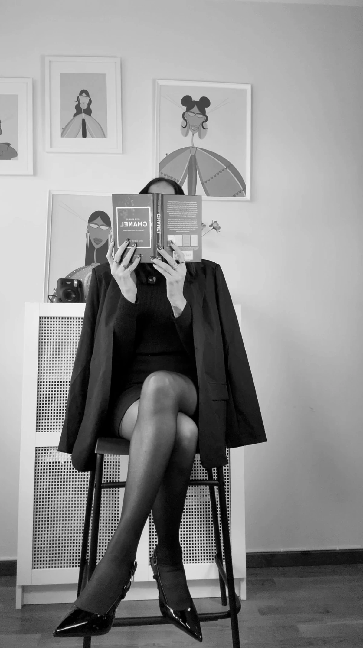 Black and white editorial portrait of Nermin seated and holding a book